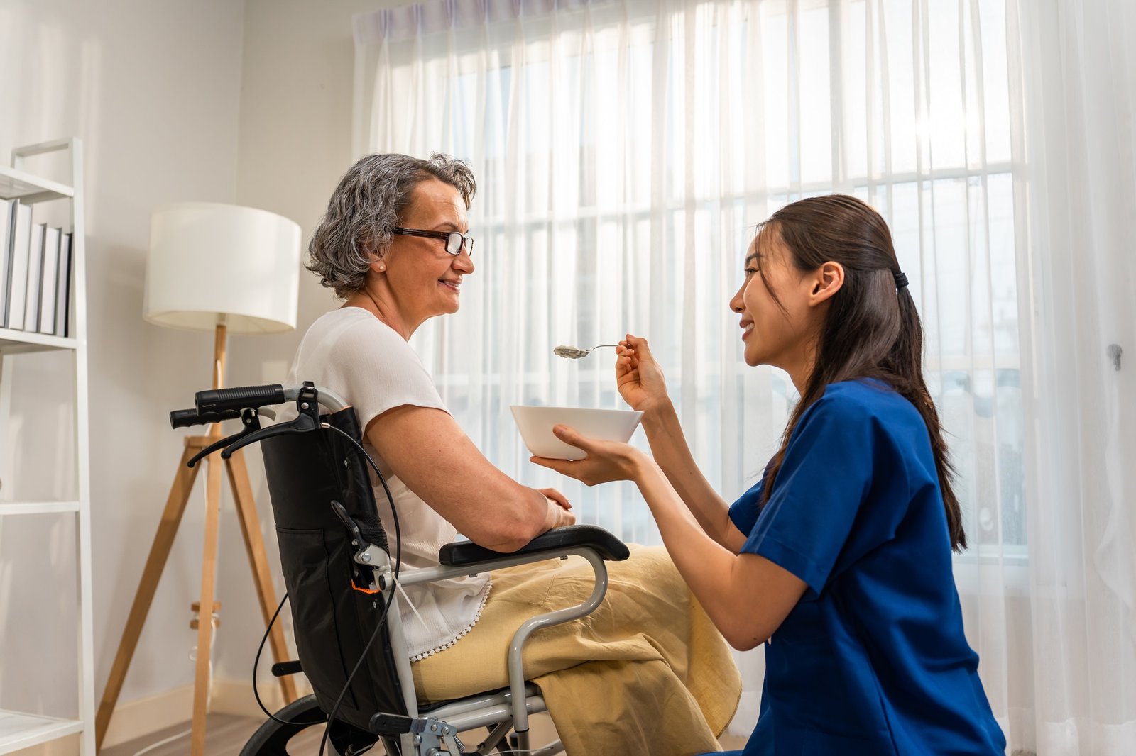 Carer helping an older woman at mealtime
