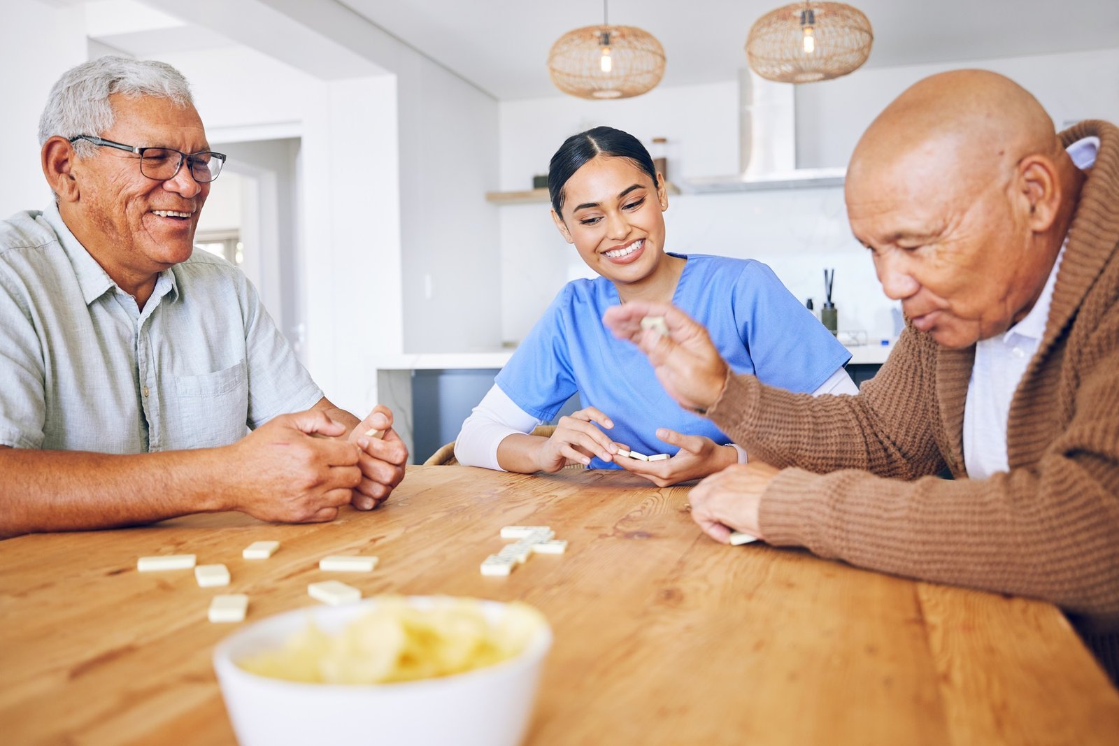 Older adults enjoying a game of dominoes with a carer